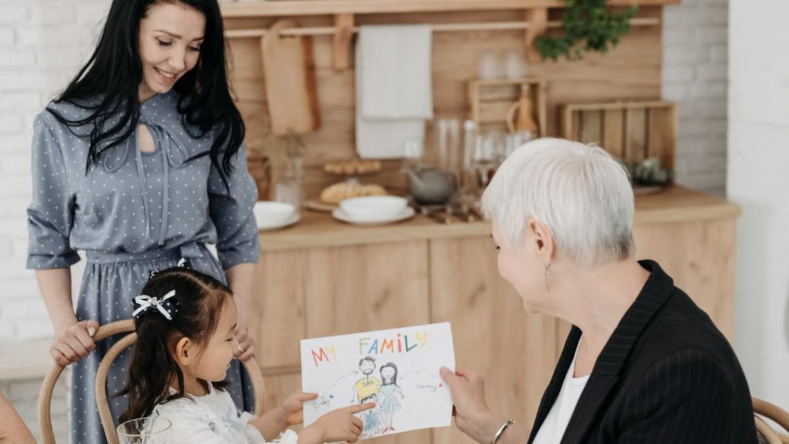 A family sharing a joyful moment as a child presents a drawing, emphasizing love and connection.